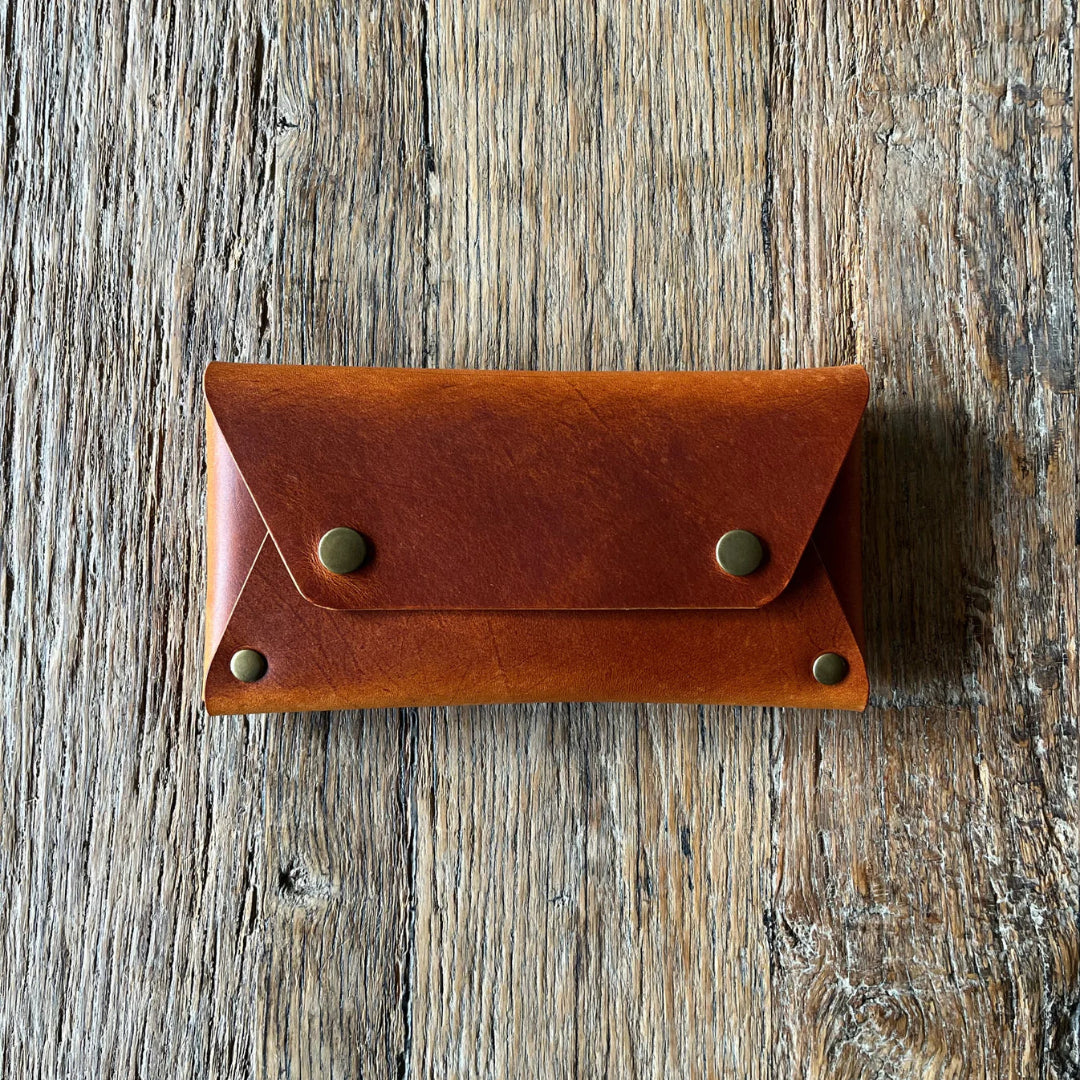 Brown leather wallet with gold rivets on a wooden surface