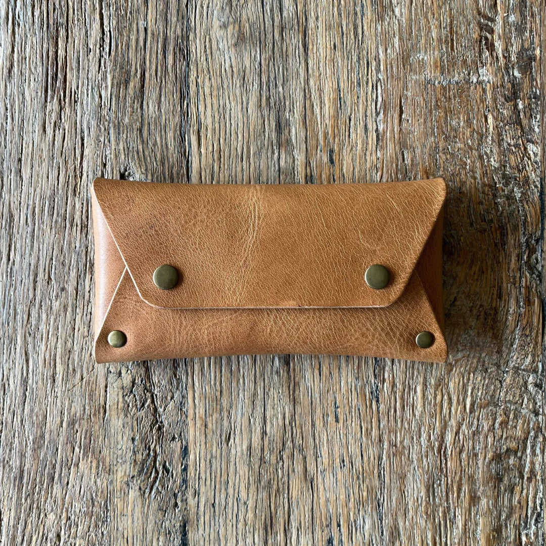 Brown leather wallet with gold studs on a wooden surface