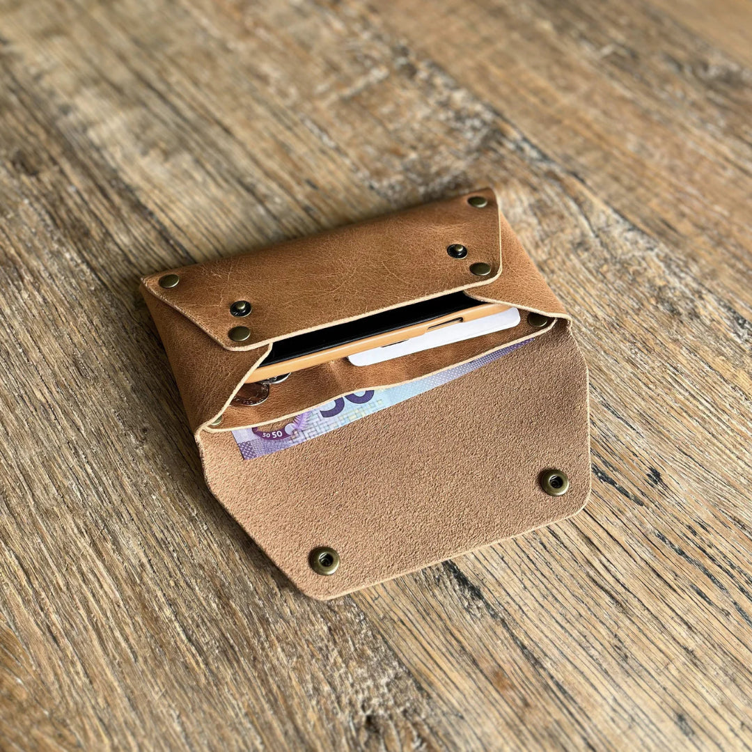 Brown leather wallet with money on a wooden surface