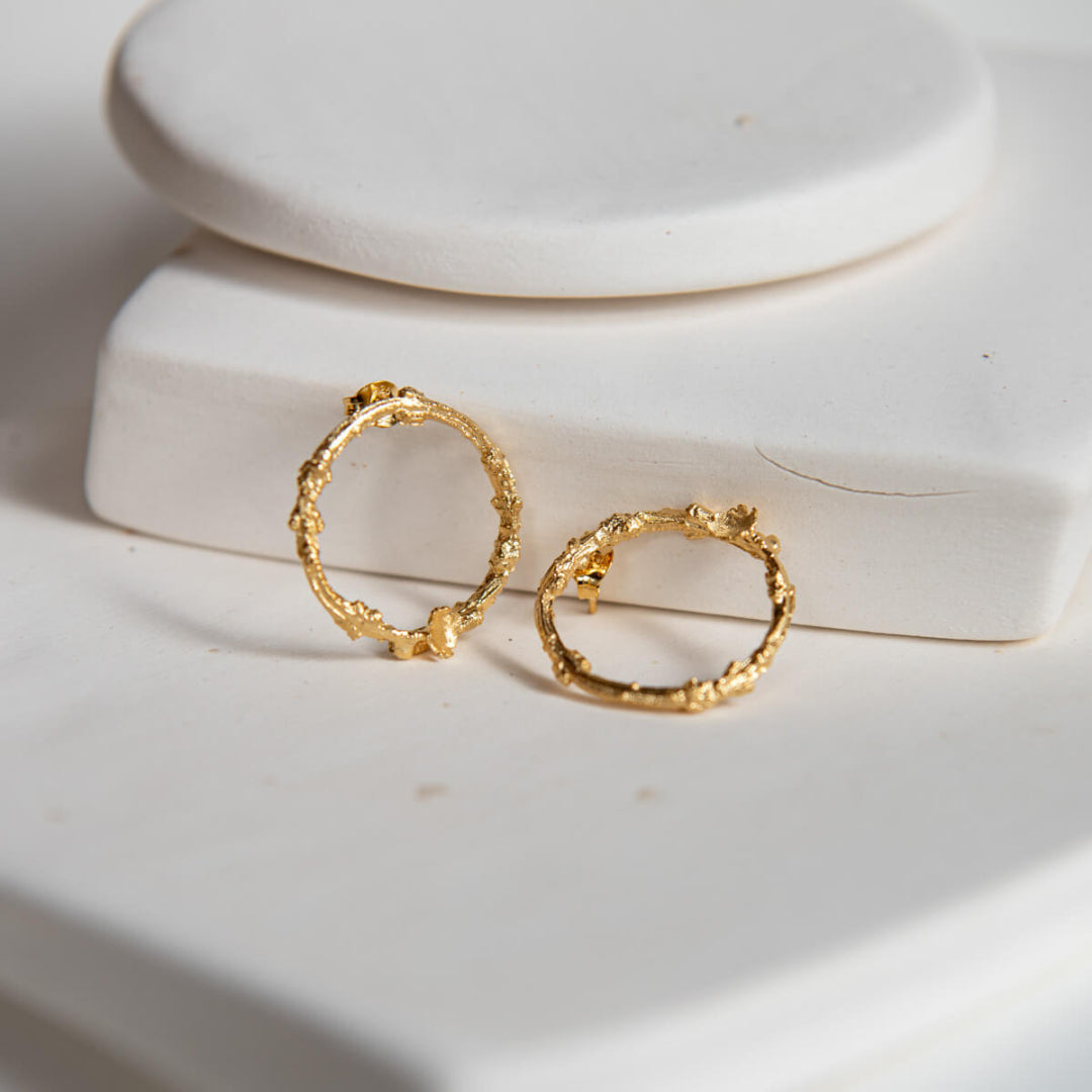 Gold hoop earrings on a white ceramic dish
