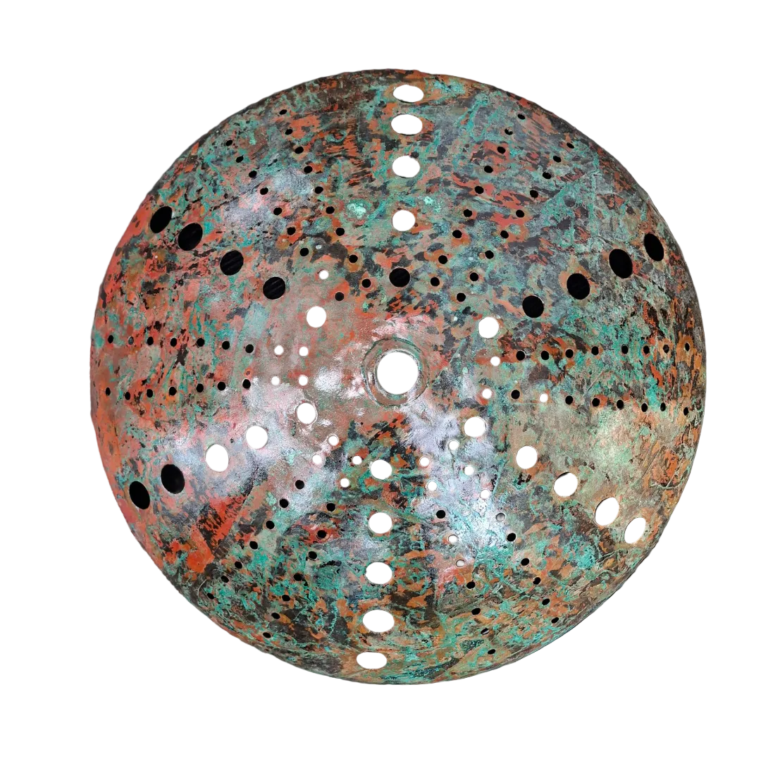 Patina'd copper kina sculpture with holes on a textured surface