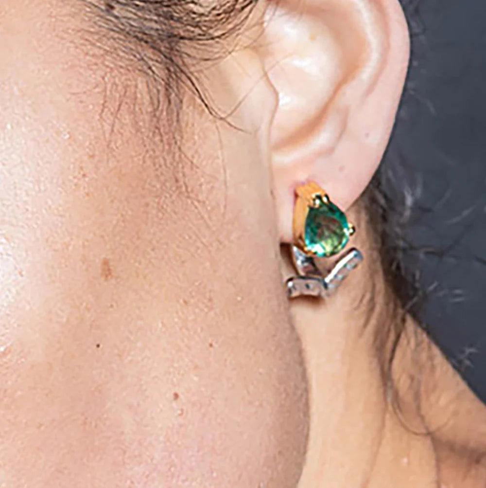 Close-up of an ear wearing a green gemstone earring.