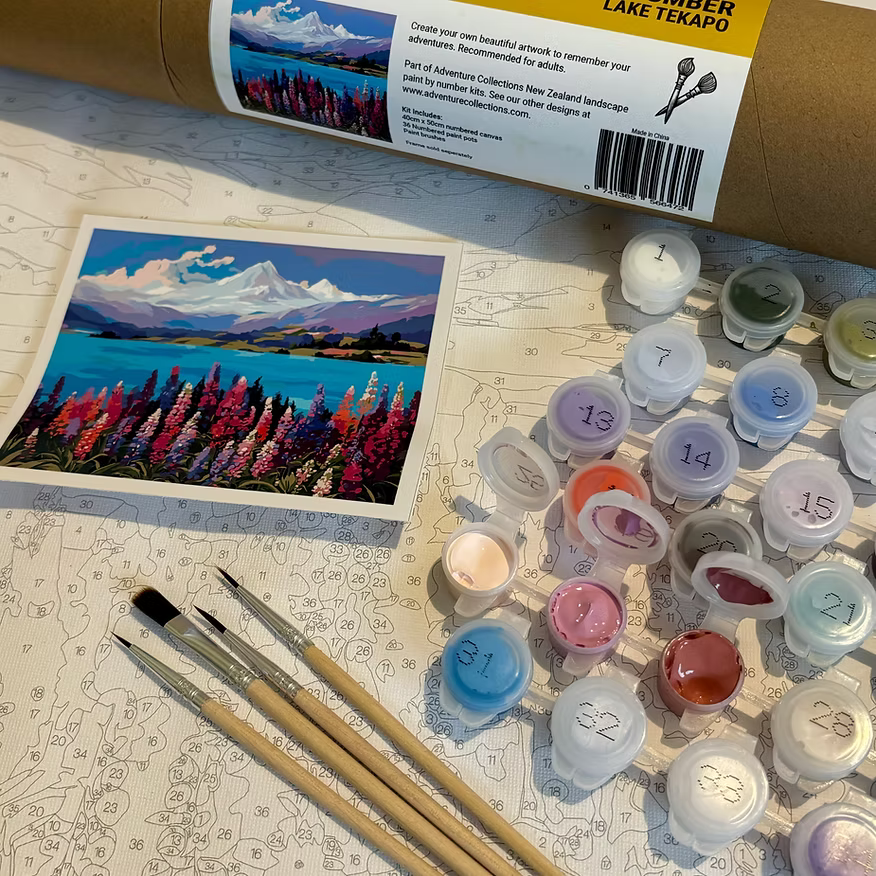 Art supplies including paint tubes, brushes, and a painted landscape on a table.