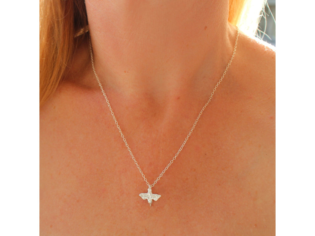 Close up of a person wearing a Shiny Silver Diving Kingfisher pendant on a chain.