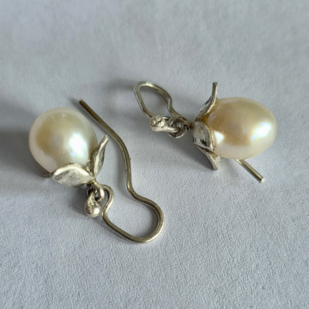 Pearl earrings with silver hooks on a light gray background