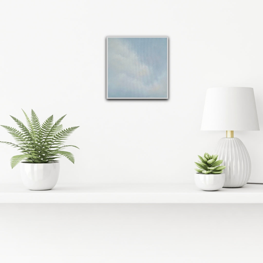 Modern interior with a plant, lamp, and framed artwork on a white wall.