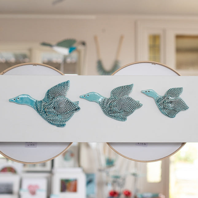 Decorative wall art with three teal ducks on a white background