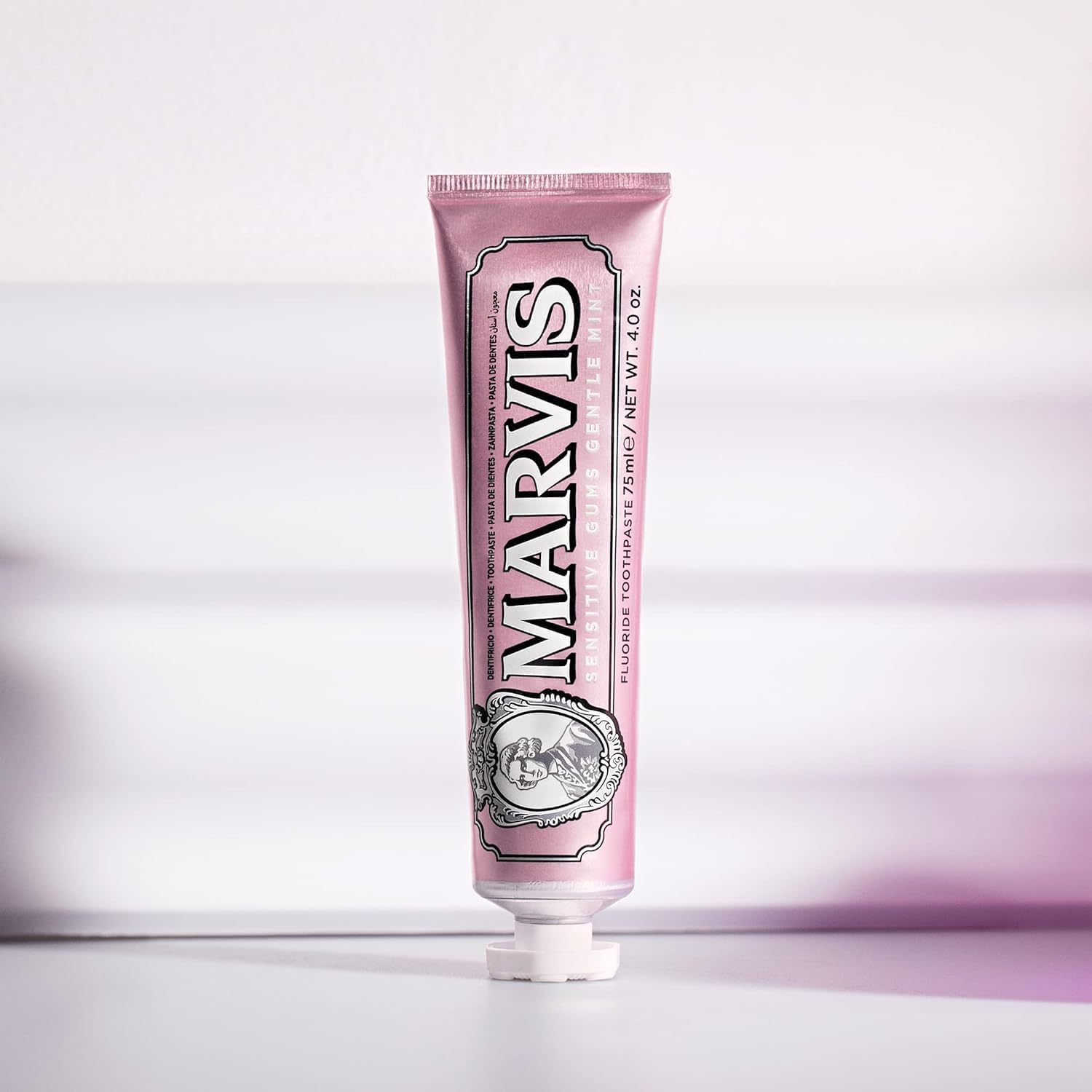 Pink toothpaste tube with 'Marvis' branding on a light purple background