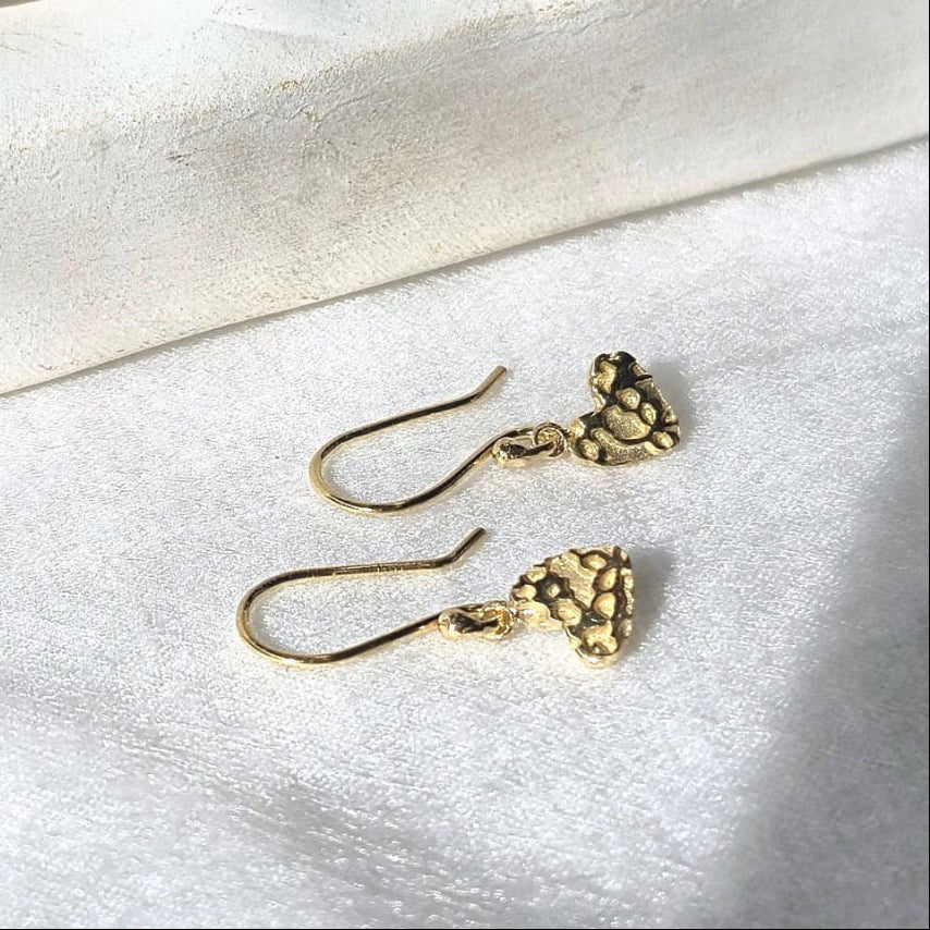 Gold earrings on a light stone surface