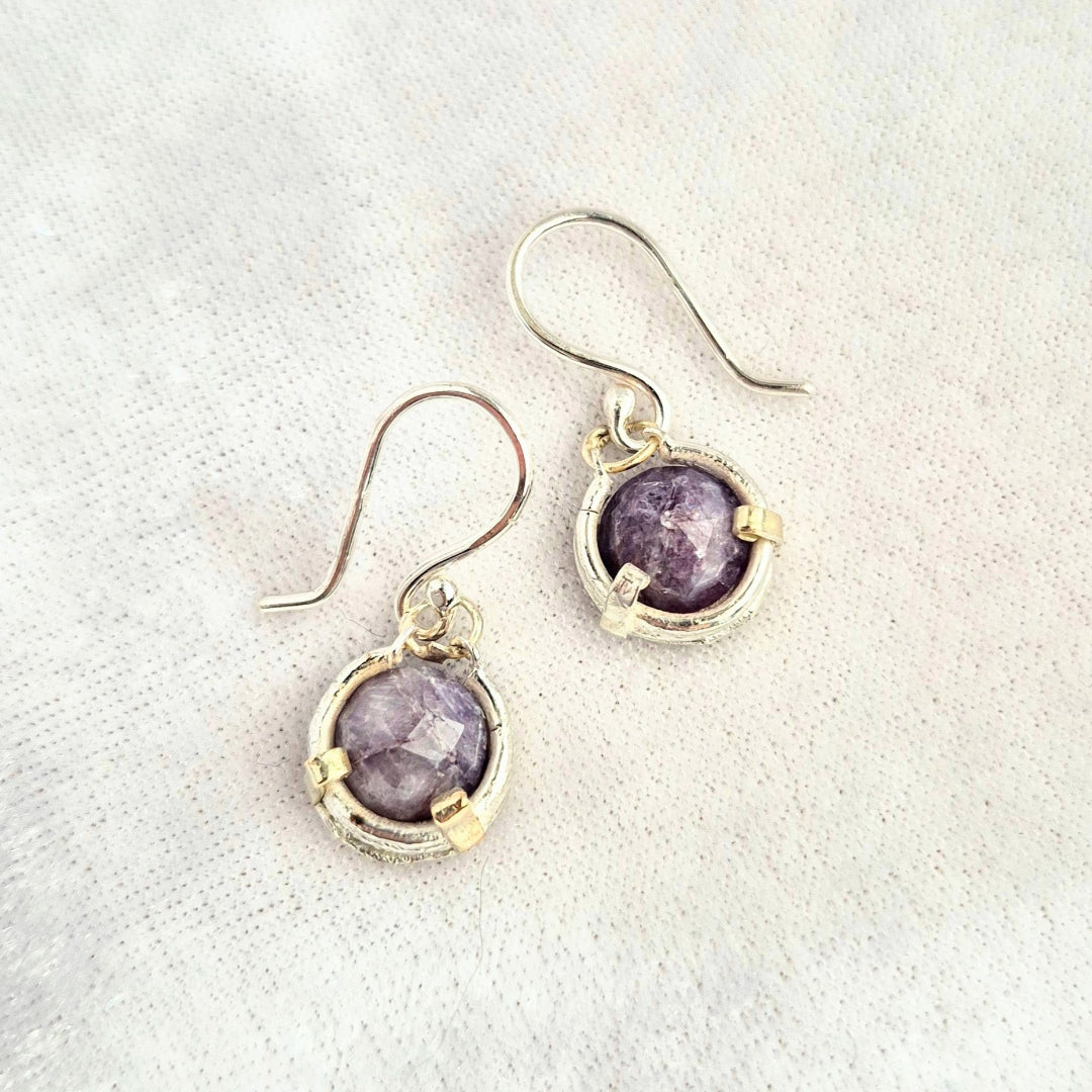 Pair of earrings with blue saphire  gemstones on a white background