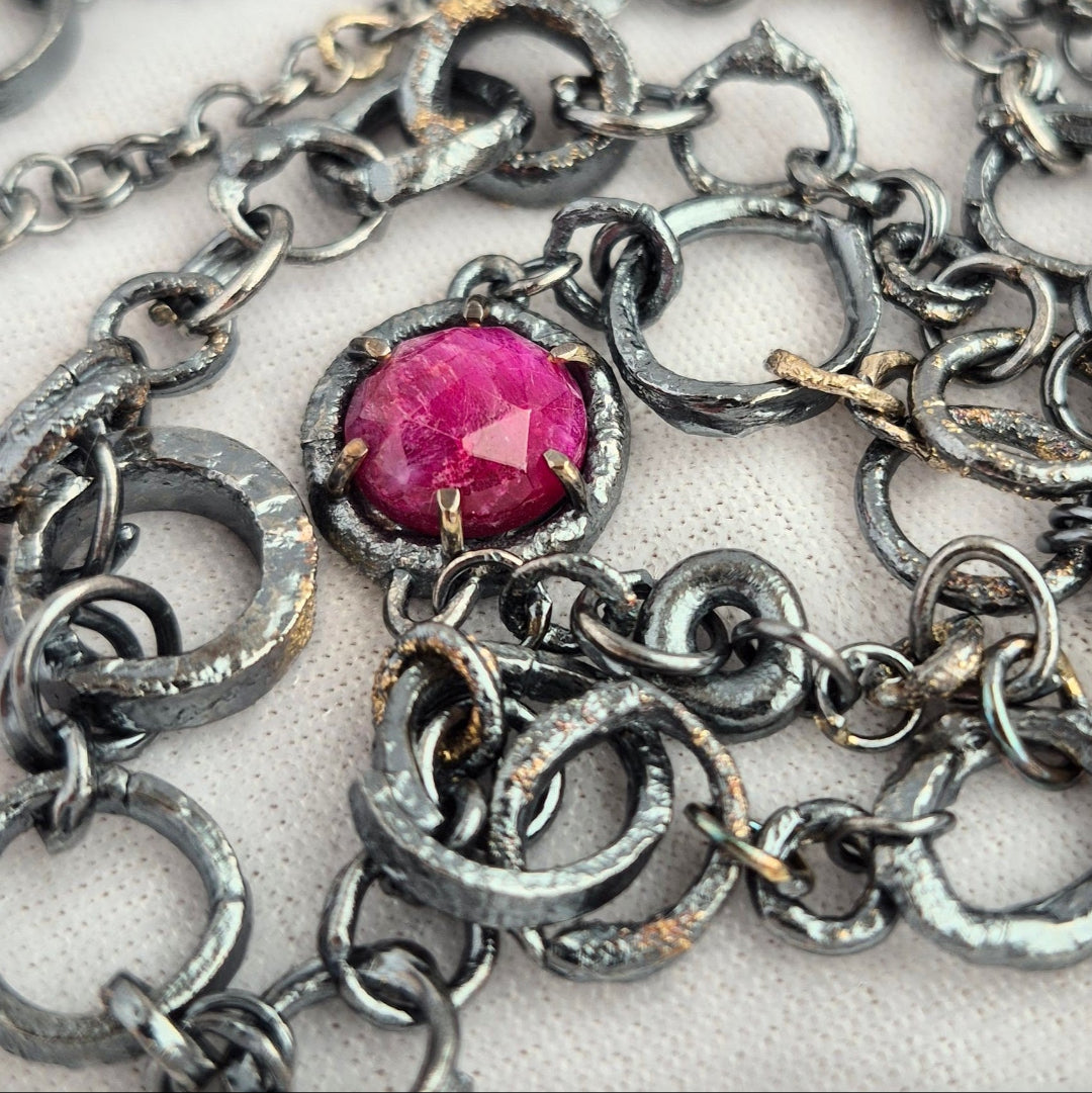 Silver chain necklace with a pink ruby on a white background