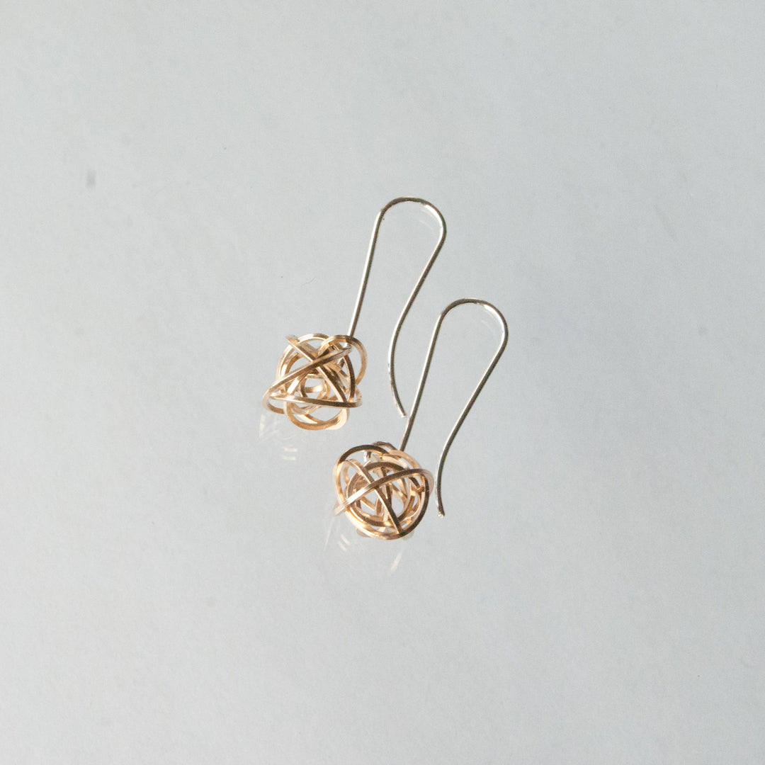 Pair of gold earrings on a light gray background