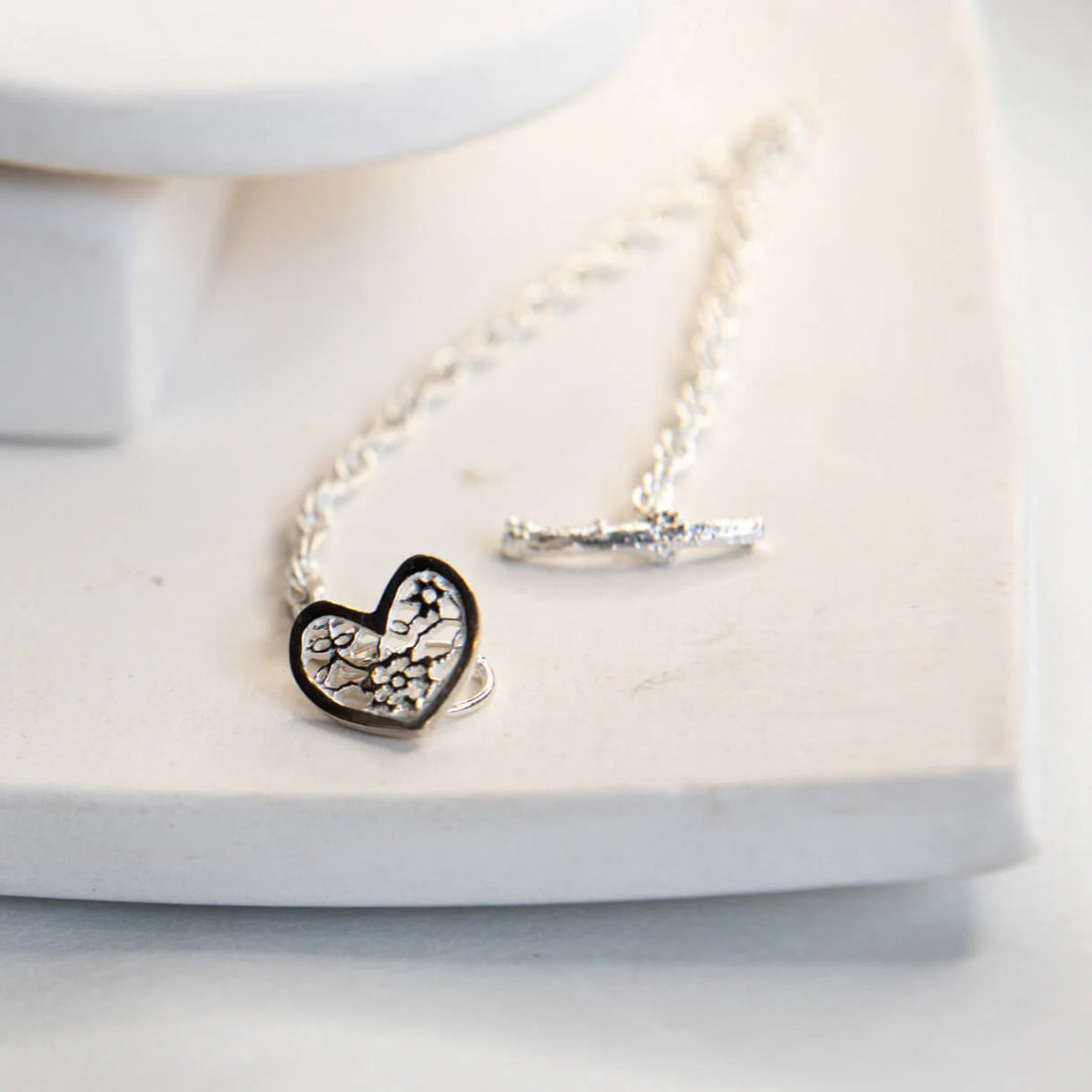 Silver bracelet with a heart-shaped charm on a white surface