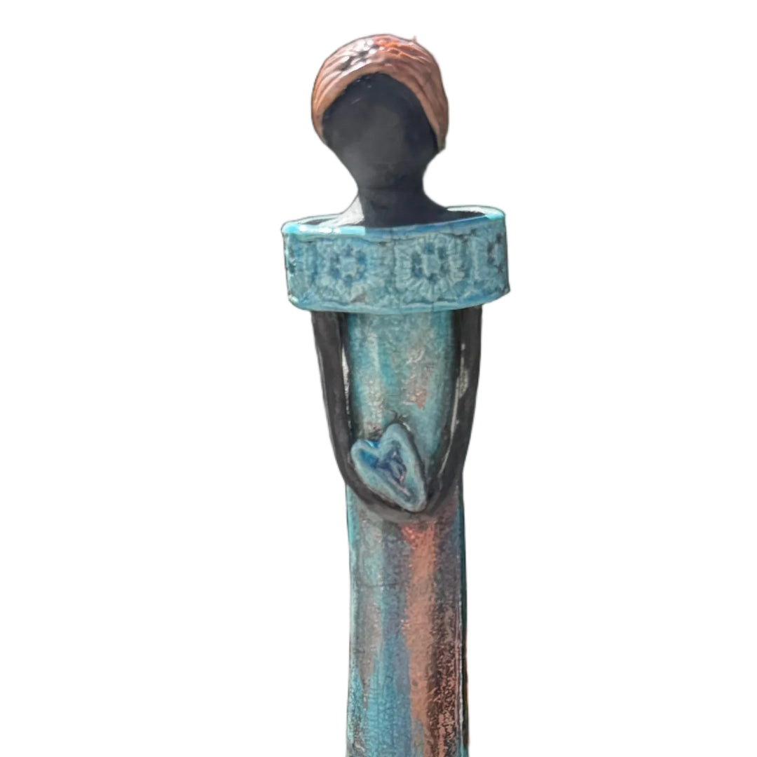 Close up view of a ceramic tall lady figurine  holding a heart against a white back ground.
