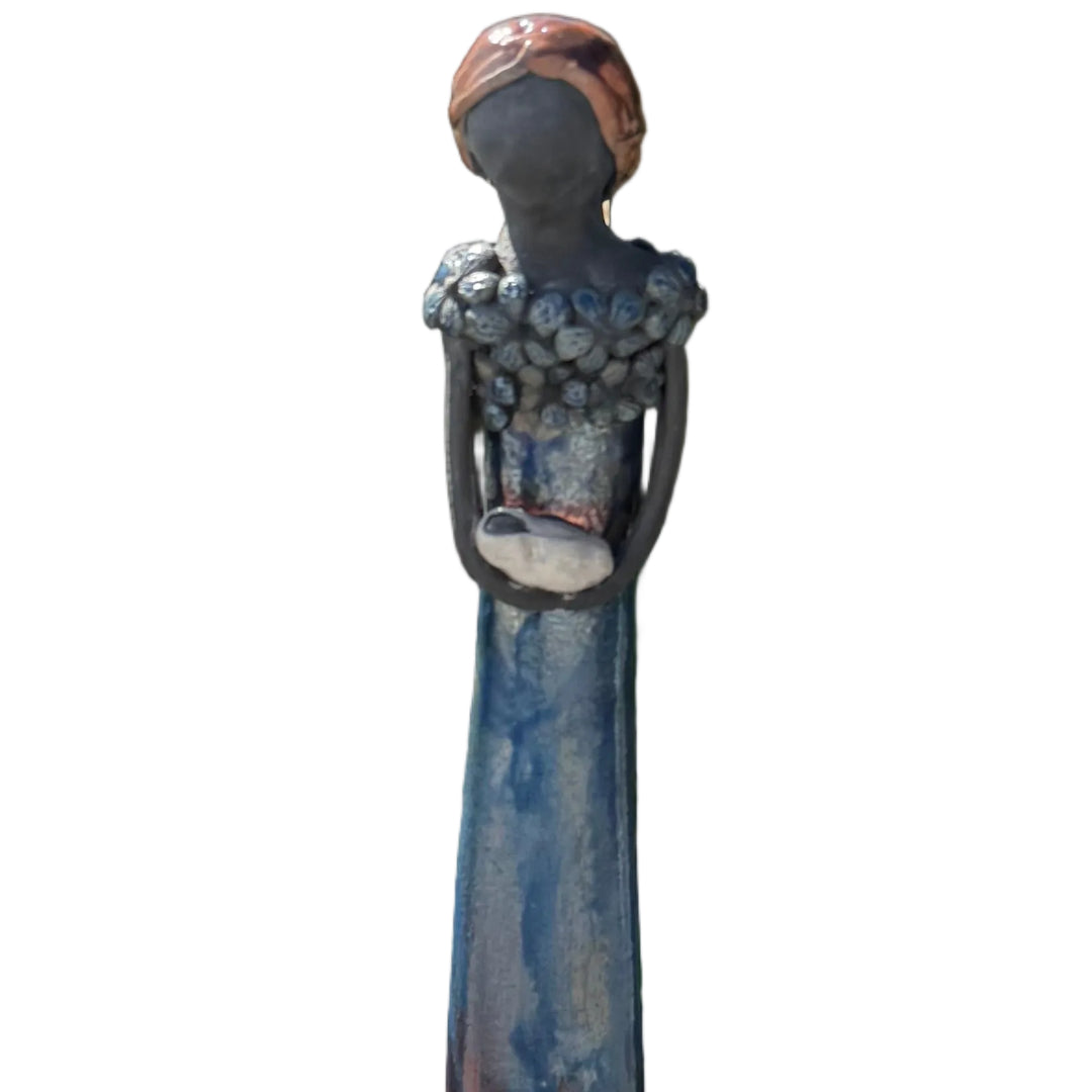 Close up view of a ceramic tall lady figurine  holding a baby against a white back ground.