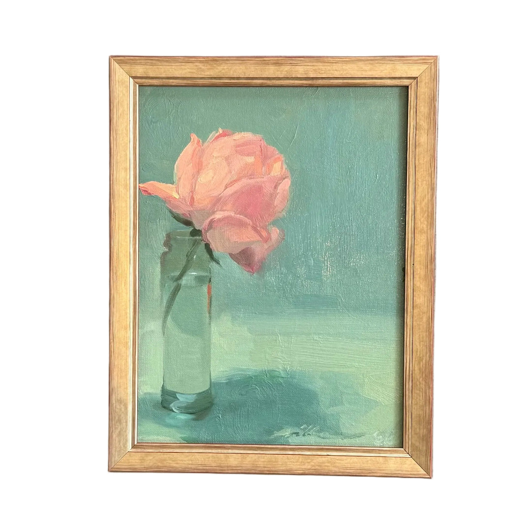 A small framed painting of a pink rose in a glass vase against a teal background, on a white background.