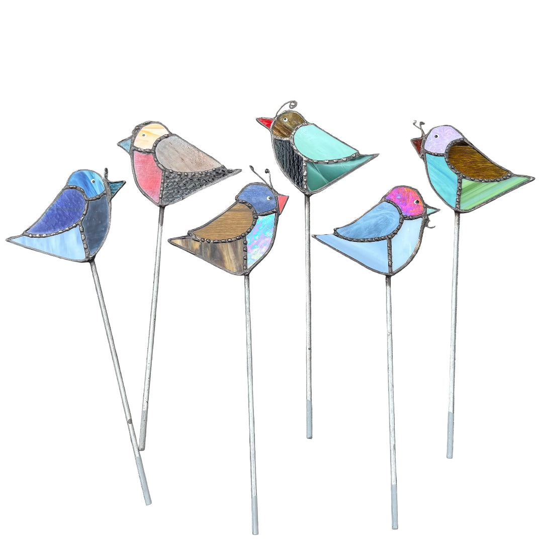 Six colorful stained-glass-style bird garden stakes with long metal legs, arranged on a white background.