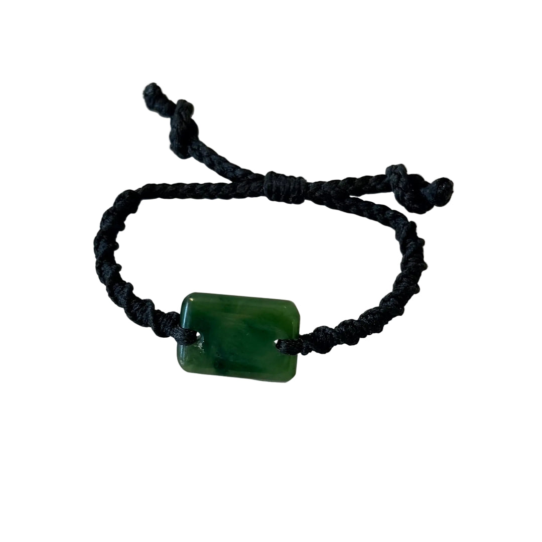 A black adjustable cord bracelet featuring a polished green rectangular greenstone or pounamu pendant, displayed on a white background.