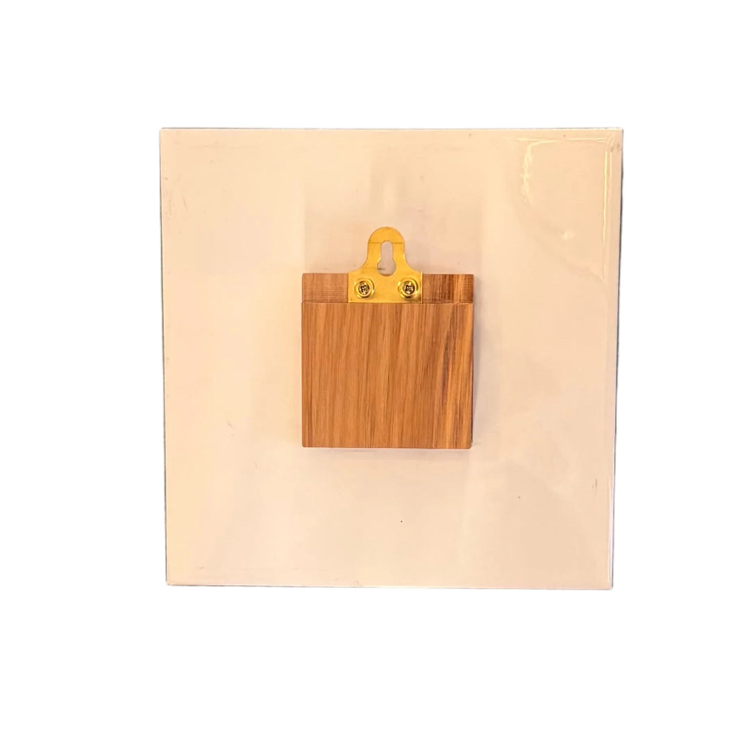 Back view of a ceramic tile with wood block to off set it and a metal loop for hanging it on a wall.