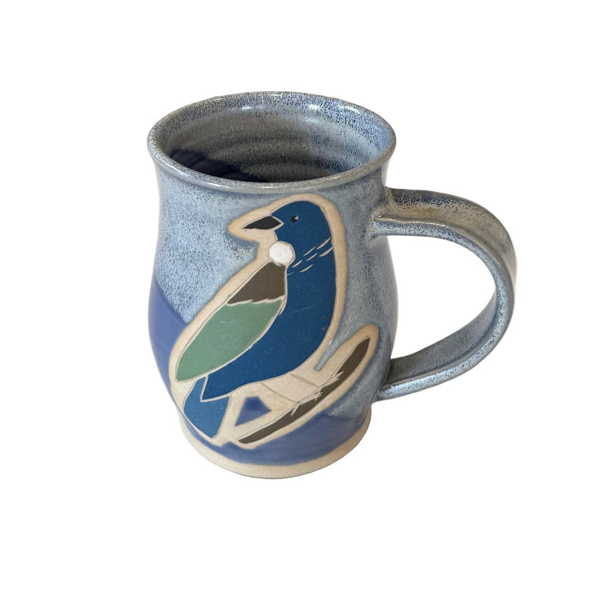 Blue ceramic mug with tui bird design on a white surface