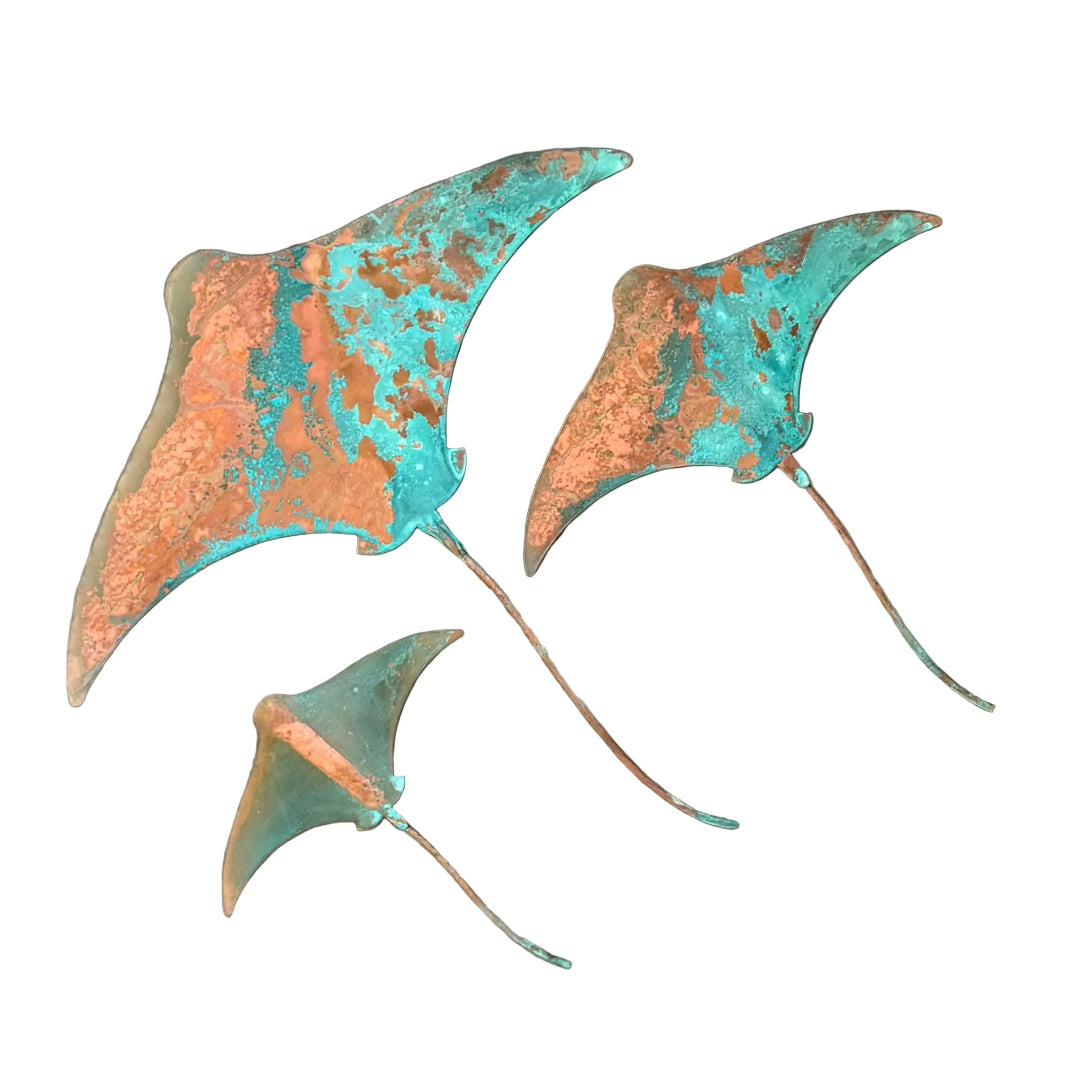 Three copper and blue patina'd stingray wall scuptures on a white surface