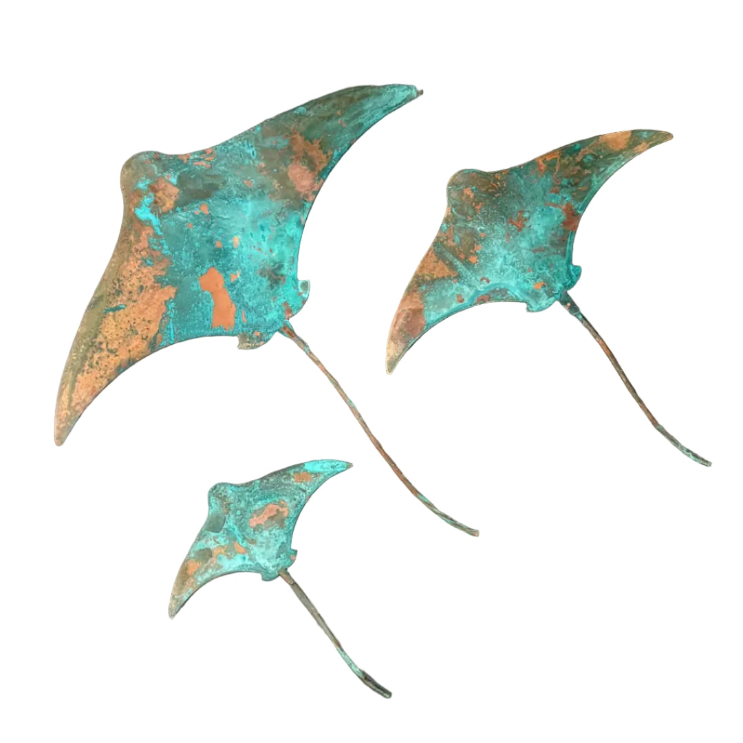 Three blue patina'd copper stingray wall sculptures on a white surface