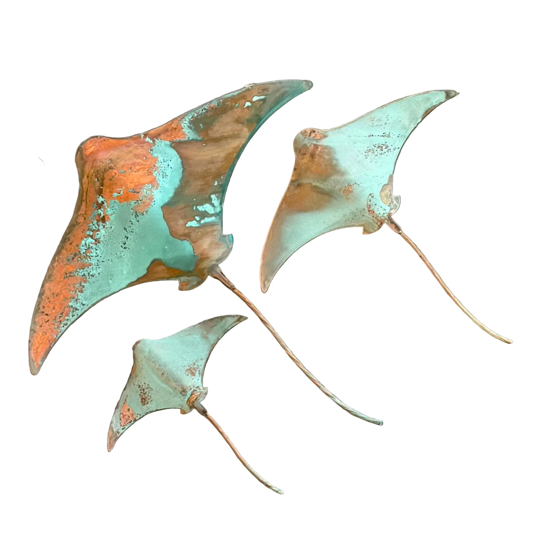 Three patina'd copper stingray wall sculptures on a white background