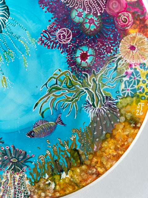 Colorful underwater scene with fish and coral on a circular art piece.