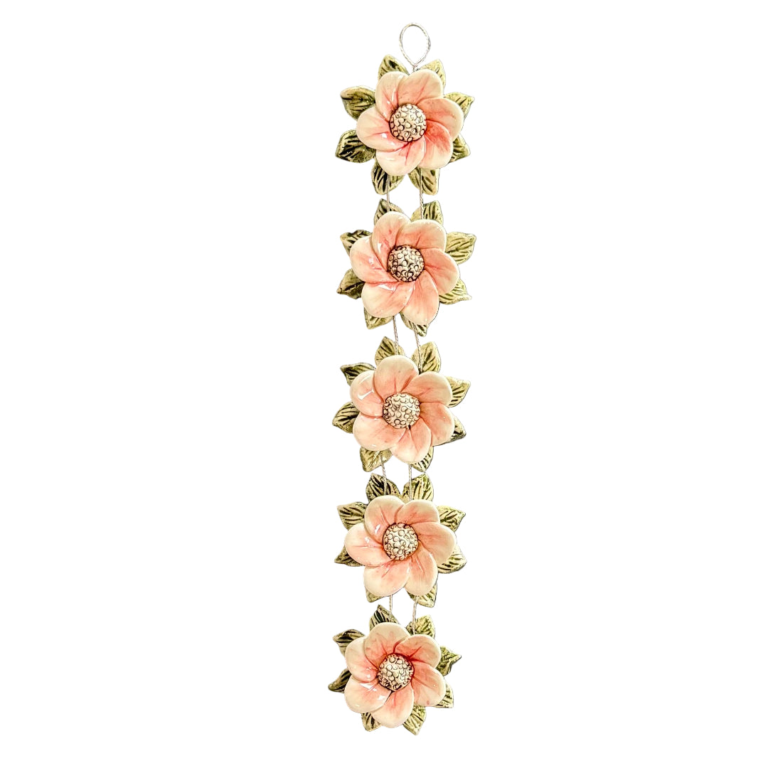 Decorative wall hanging with ceramic pink flowers on a white background