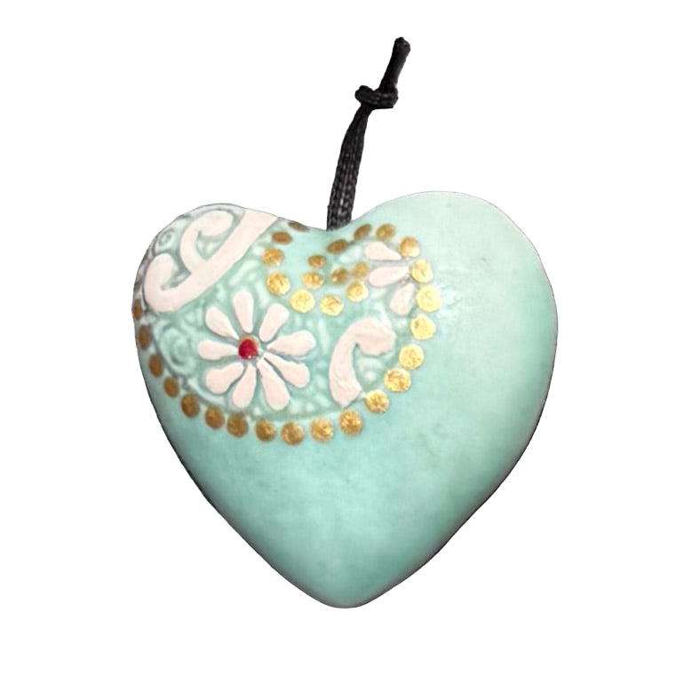 Embossed ceramic hanging heart with floral patterns on a white surface