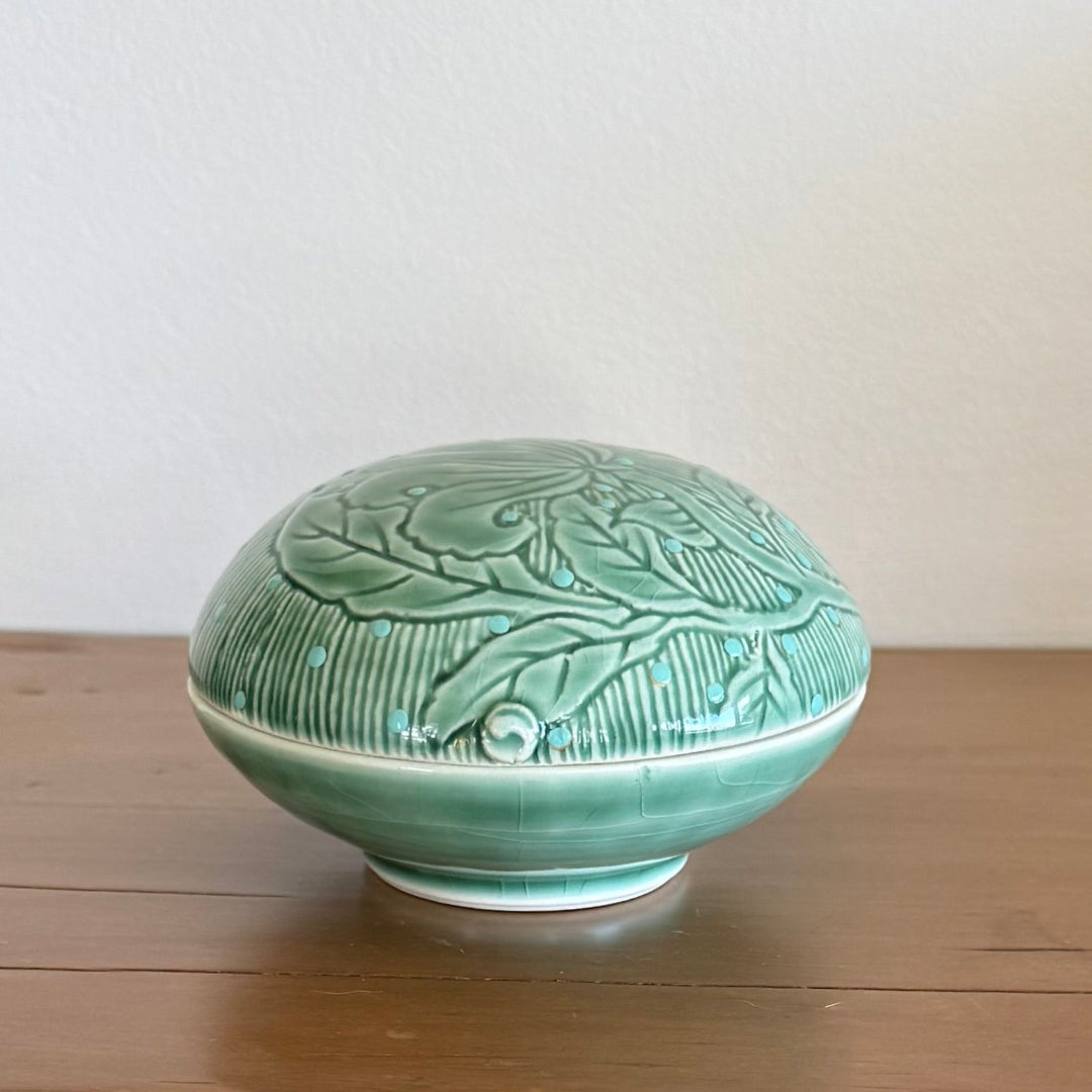 Green ceramic bowl with leaf patterns on a wooden surface
