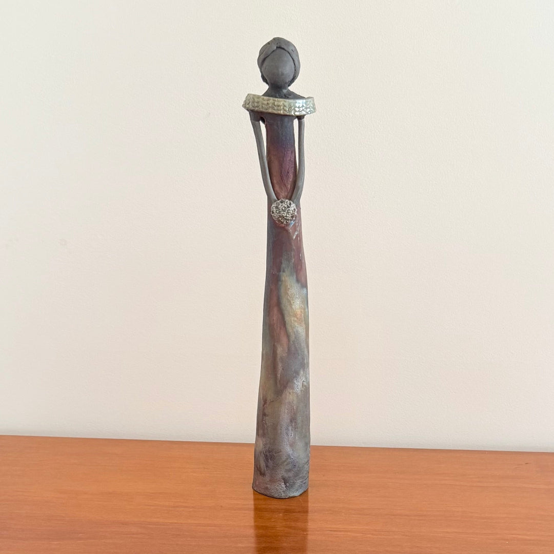 Decorative ceramic sculpture of a woman on a wooden surface with a plain background