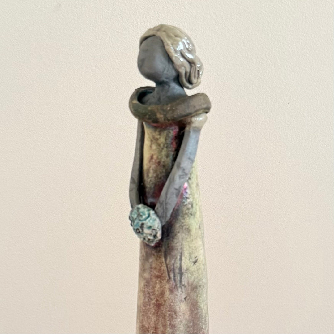 Decorative ceramic sculpture of a woman on a plain background