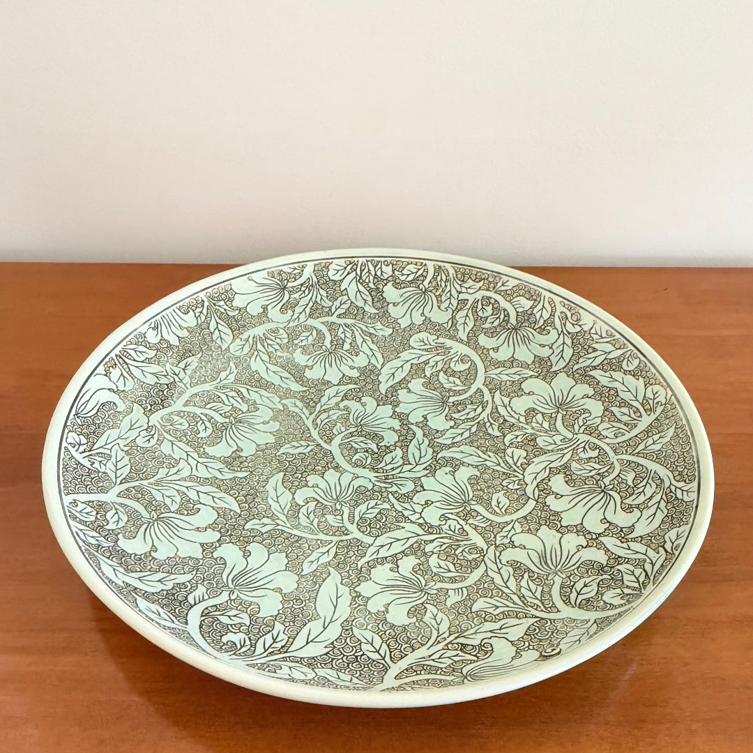 Decorative plate with intricate floral pattern on a wooden surface