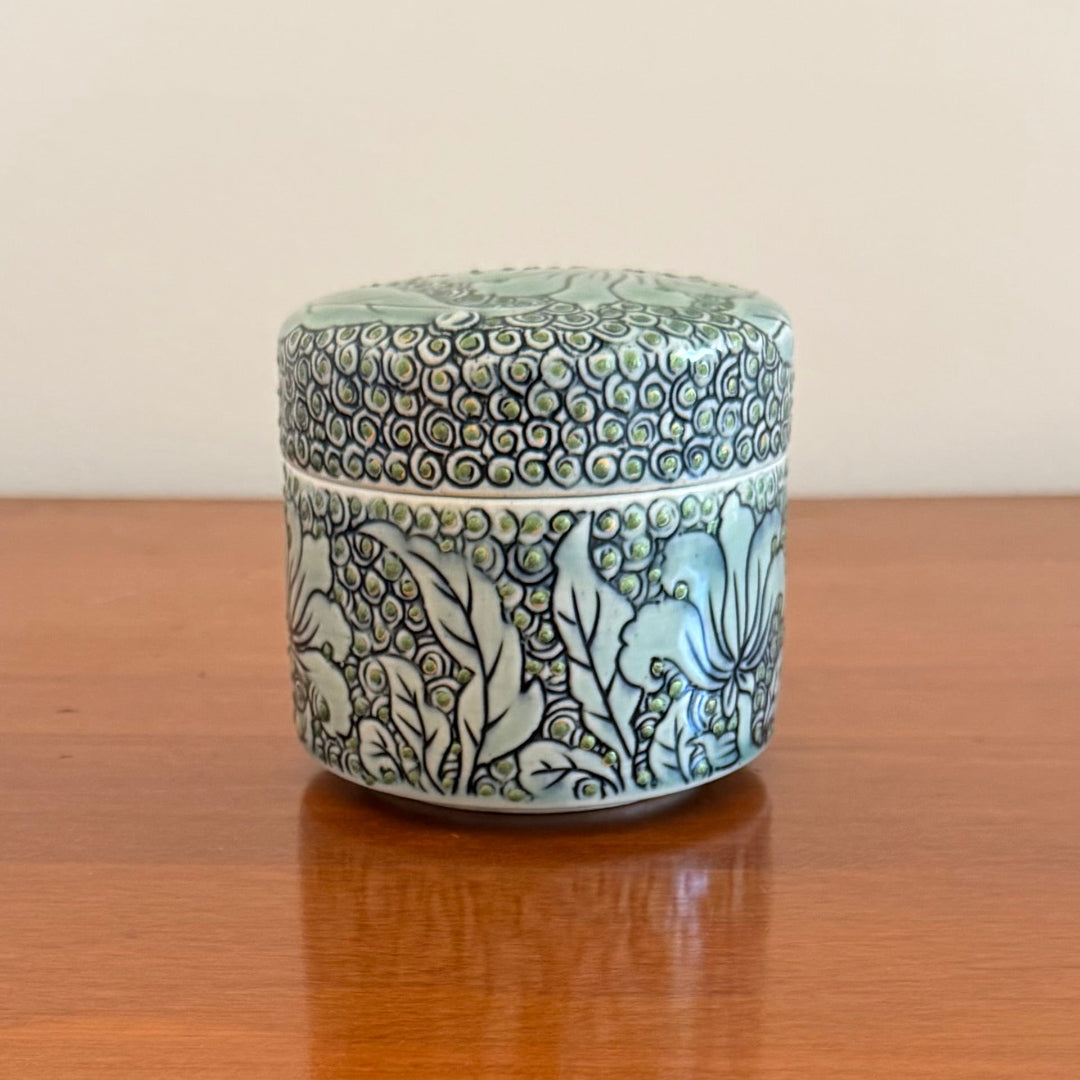 Decorative ceramic jar with floral patterns on a wooden surface