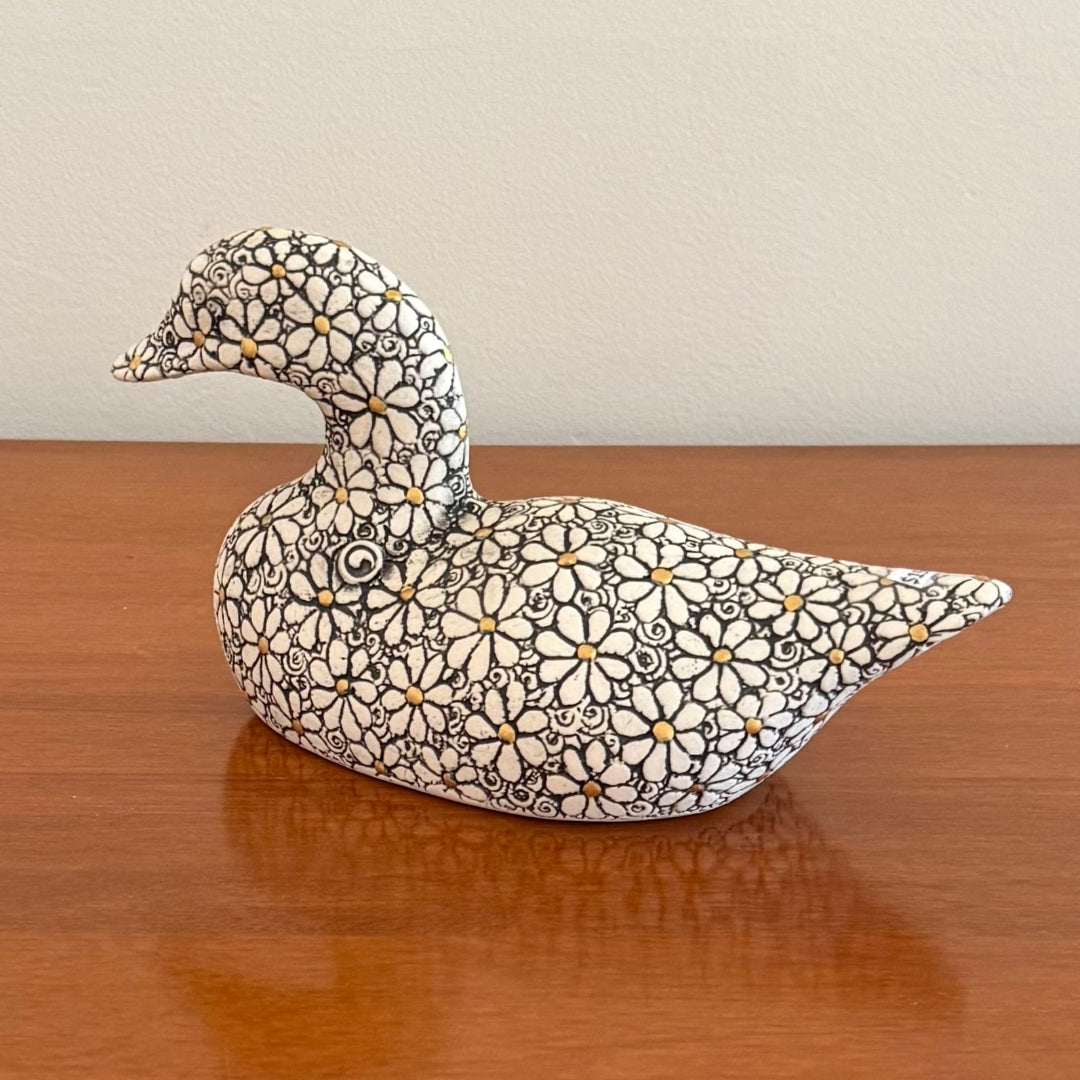 Decorative duck figurine with floral patterns on a wooden surface
