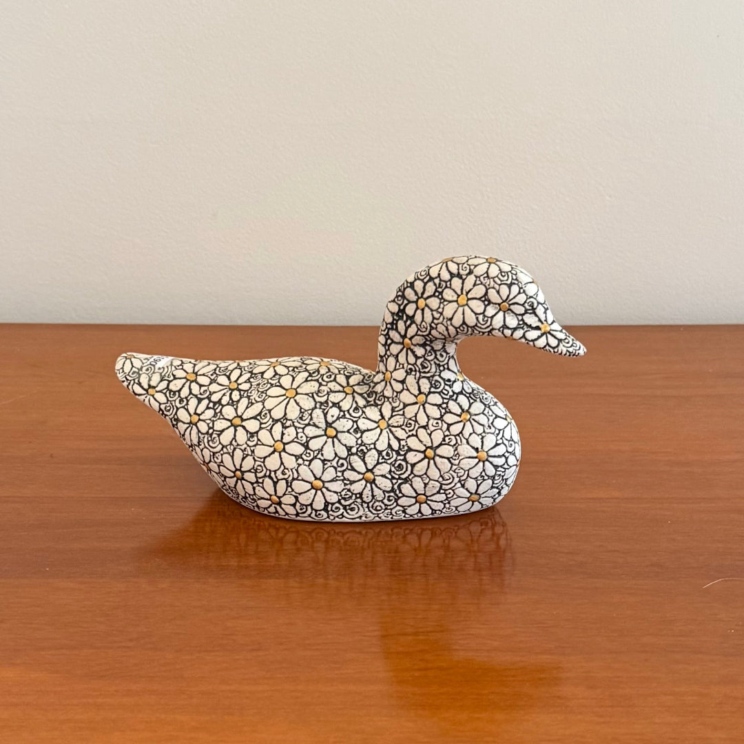 Decorative duck figurine with floral pattern on a wooden surface