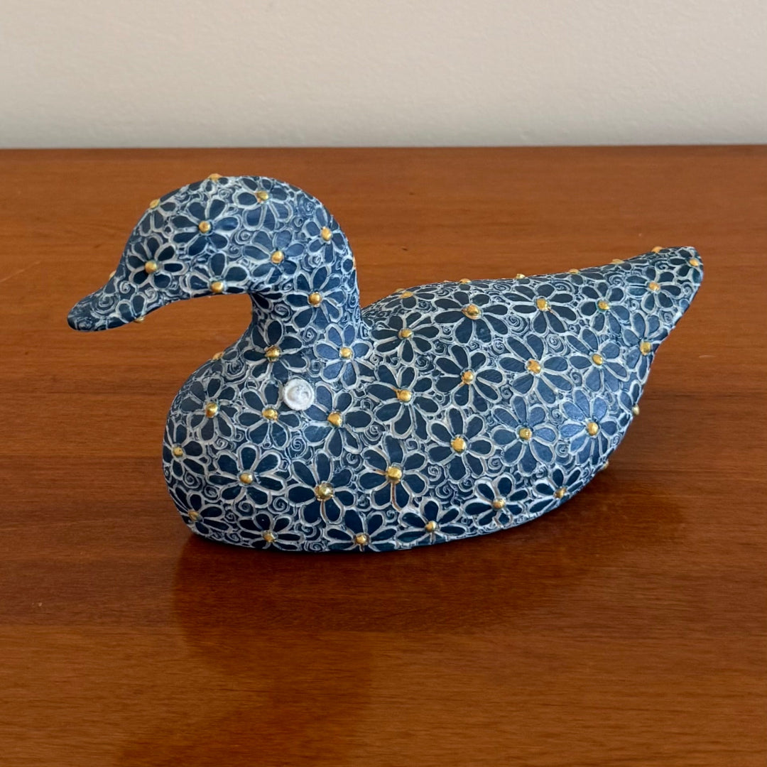 Decorative duck with floral pattern on a wooden surface