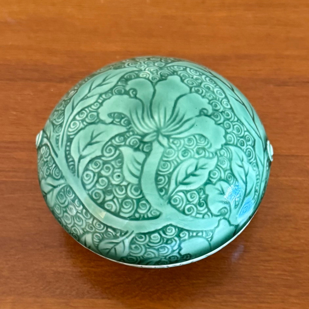 Green decorative ceramic dish with lid  on a wooden surface