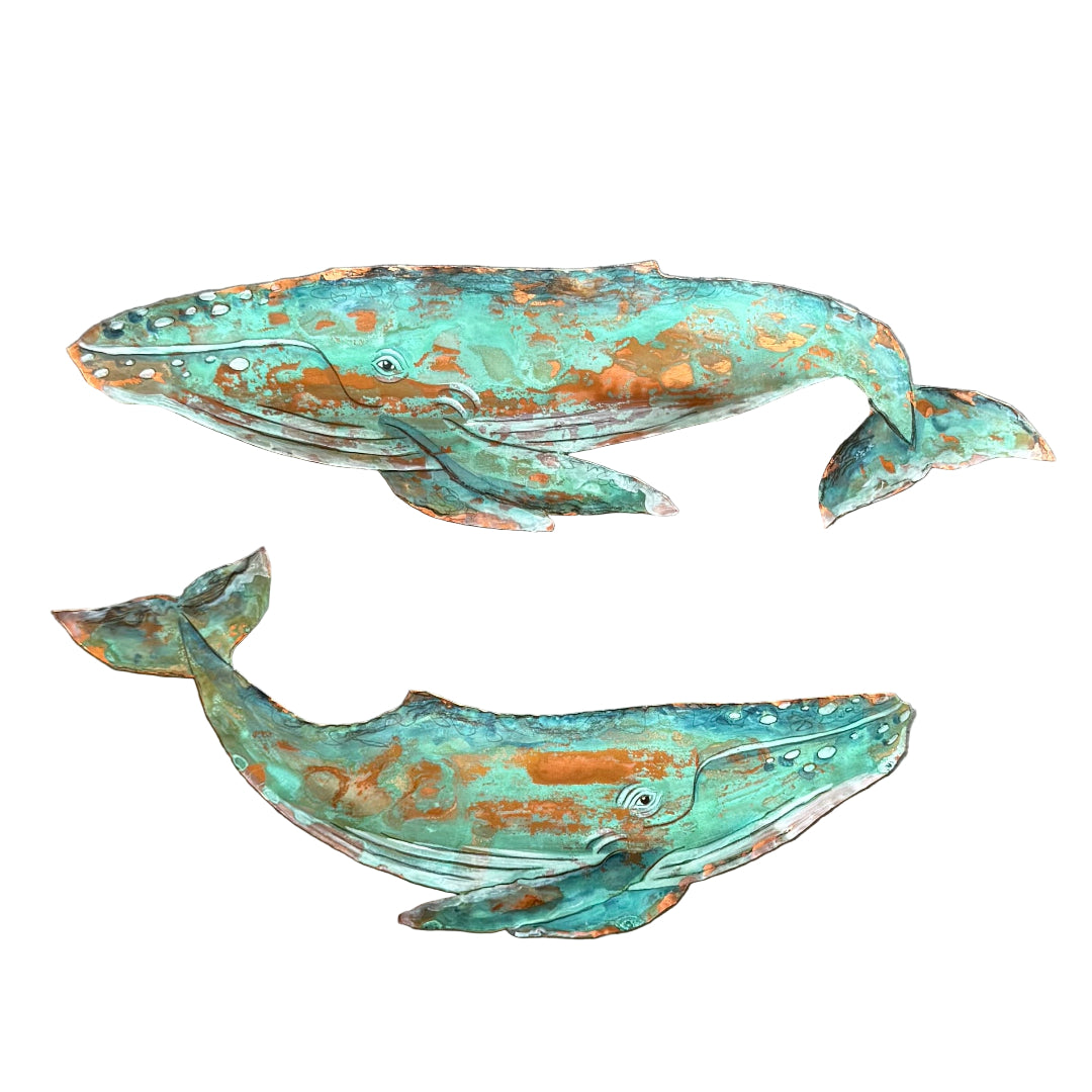 Two copper whales with verdigris patina on a white background