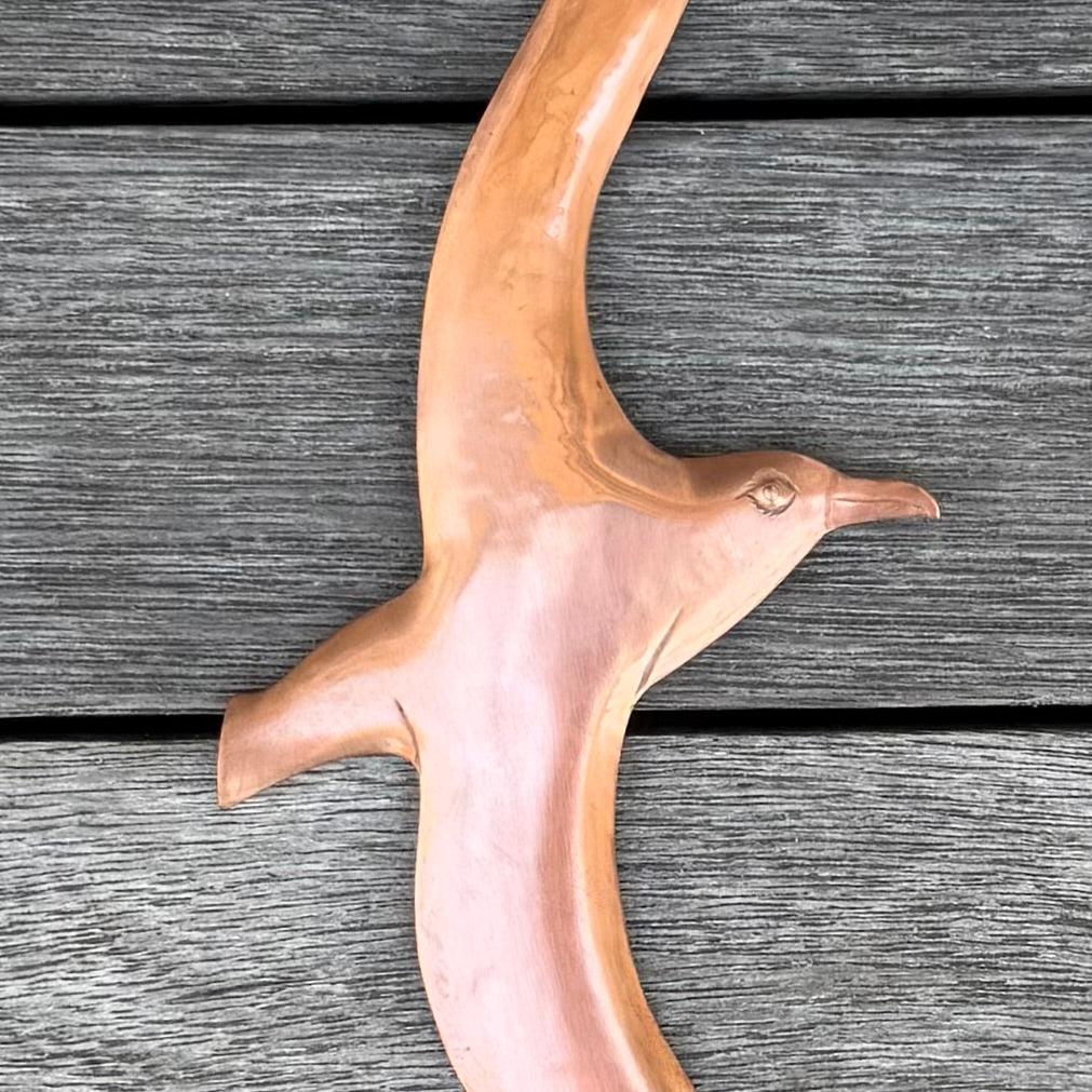 Close up of a copper Albatross bird sculpture on a wooden surface
