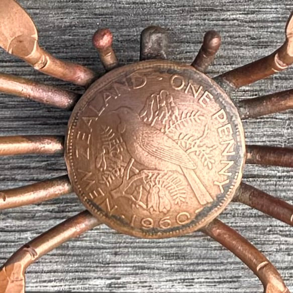 Copper New Zealand One Penny Coin as body of a crab sculpture on wooden background