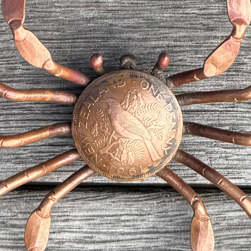 Copper crab with penny body on a wooden surface