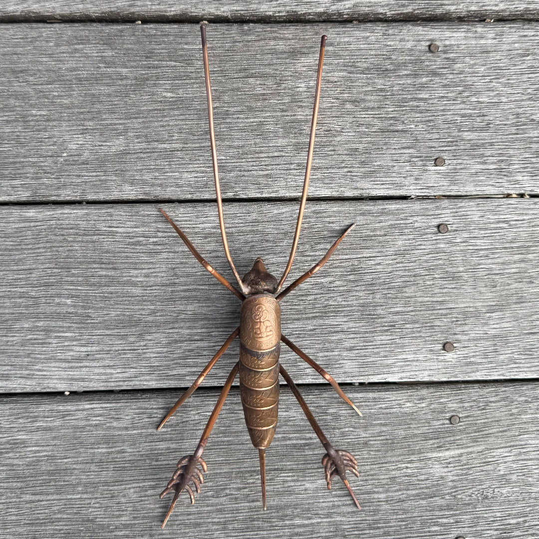Copper Weta sculpture on a wooden surface