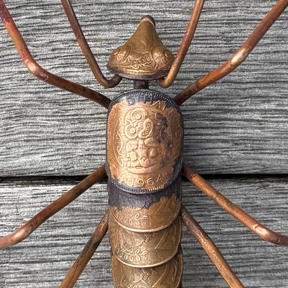 Copper Weta made from copper coins on a wooden surface