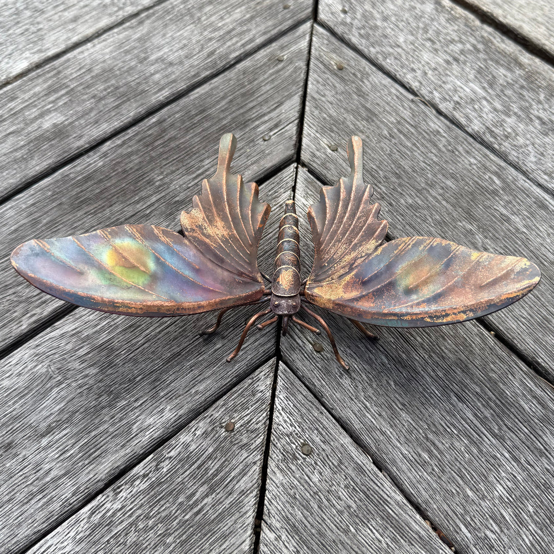 Decorative copper butterfly on a wooden deck