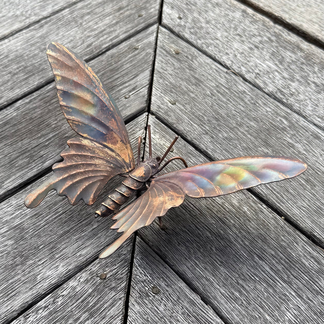 Copper butterfly sculpture on a wooden surface