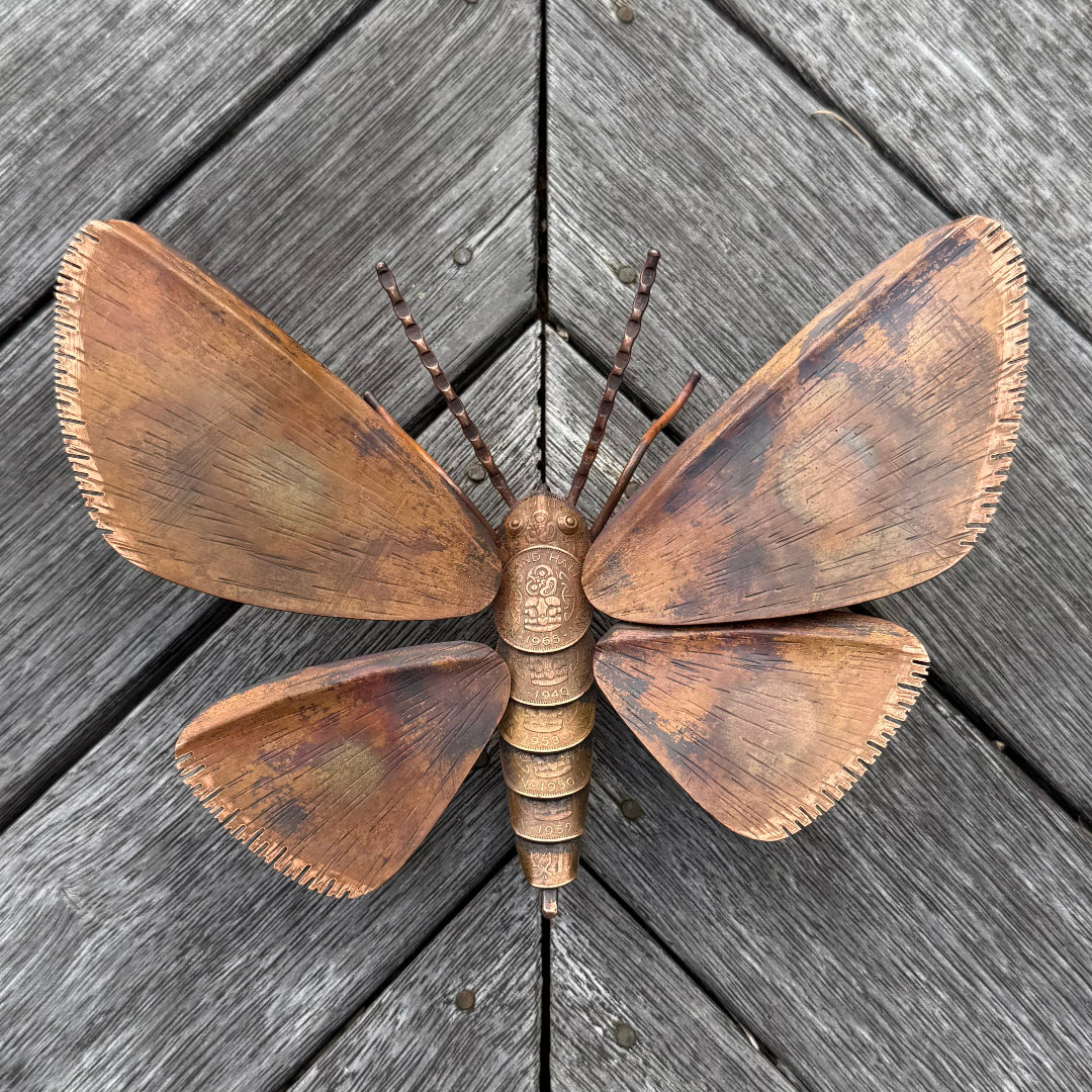 Copper butterfly sculpture on a wooden surface