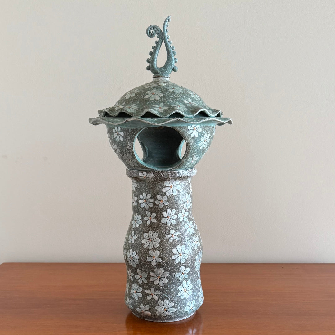 3 Piece ceramic Lantern including the base, lantern , and finial on a wooden surface.