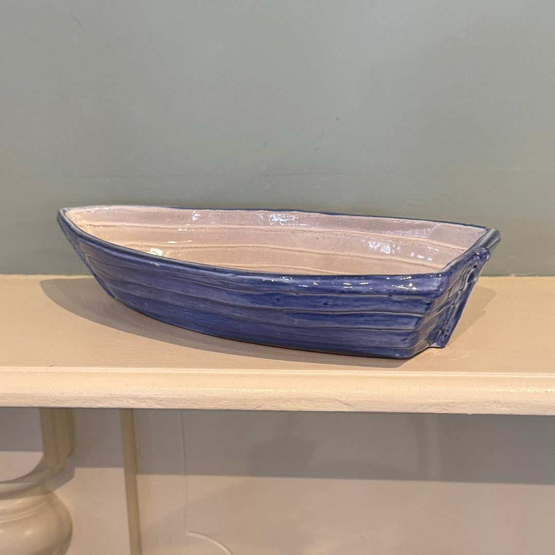 Blue ceramic dinghy on a cream mantle piece with a blue background